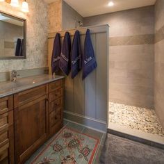 a bathroom with two towels hanging on the wall and a rug in front of it