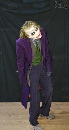 a man dressed as the joker standing in front of a black backdrop