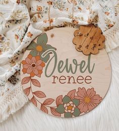 a wooden sign with flowers on it that says devel renee next to a white blanket