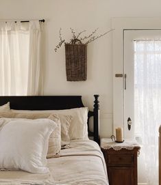 a bed with white sheets and pillows next to a wooden dresser in front of a window