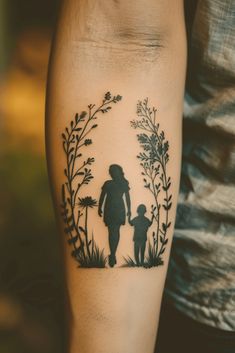 a woman with a tattoo on her arm holding a child's hand and walking through the grass