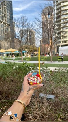 a person holding a cupcake with sprinkles on it in a park