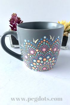 a coffee cup with colorful designs on the inside and outside, sitting next to a succulent plant