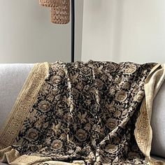 a couch with a blanket on top of it next to a lamp and floor lamp