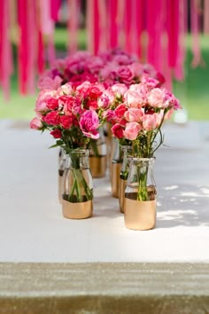 several vases filled with pink flowers sitting on top of a white table covered in glitter