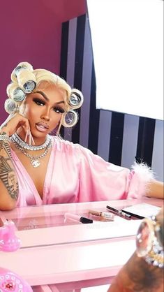 nicki mina is sitting at a table with her hair in rollers and makeup