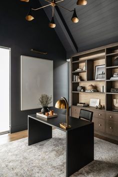 an office with black walls, gold accents and wooden shelves on either side of the desk