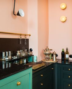 a kitchen with green cabinets and black counter tops, gold trim on the walls and brass knobs