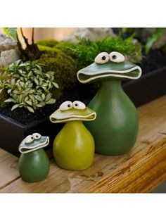 three green vases sitting on top of a wooden table next to succulent plants