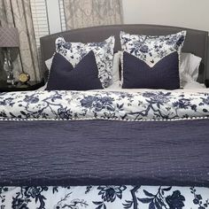 a bed with blue and white comforter, pillows and two lamps on either side