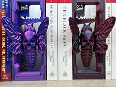 three bookshelves with purple and red bookends in front of each other