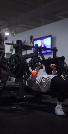 a man is doing squats with a barbell in the gym while another person watches