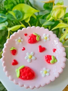 a strawberry cake sitting on top of a white plate next to green leaves and flowers