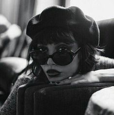 black and white photograph of a woman with sunglasses on her head sitting in a chair