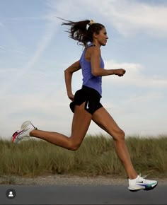 a woman is running on the road with grass in the background