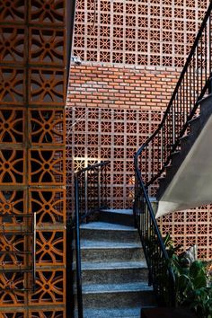 an outdoor stair case next to a brick wall and planter with potted plants