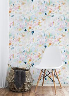 a white chair sitting in front of a wall with colorful paint splattered on it