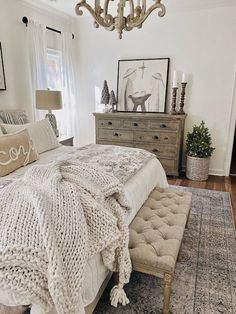 a bedroom with a bed, dresser and chandelier