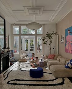 a young child sitting on the floor in front of a living room with large windows