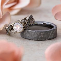 two wedding rings sitting next to each other on a table with flowers in the background