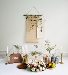 a table topped with plates and vases filled with flowers next to a wall hanging