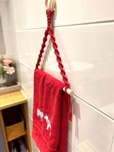 a red towel hanging from a hook on a white wall next to a wooden shelf