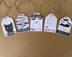 four halloween tags hanging from twine on a brown paper background with black and white designs