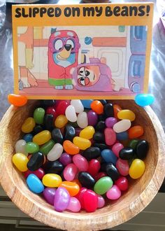 a bowl filled with jelly beans sitting on top of a counter next to a sign