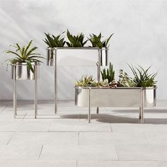 three metal planters sitting on top of a white tile floor next to each other