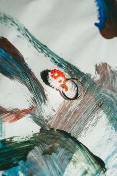 a ring sitting on top of a piece of paper with paint splattered on it