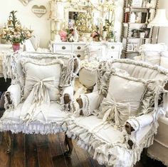 two white chairs sitting next to each other on top of a hard wood floor in front of a mirror