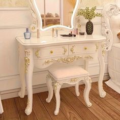 a white dressing table with a mirror and stool next to it on a hard wood floor