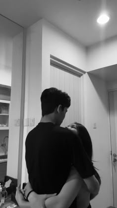 a man and woman hug each other in the kitchen