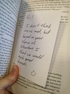 a hand holding an open book with writing on it