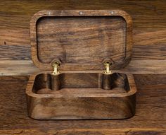 an empty wooden box with two brass handles on a wood surface, showing the inside and outside compartments