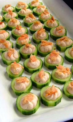 small cucumbers with shrimp on them sitting on a white platter, ready to be served