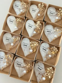 twelve white heart shaped ornaments in a box with gold leaves and pearls on the sides