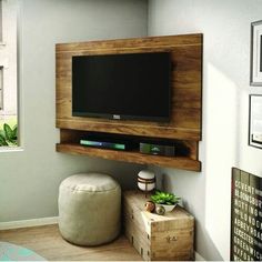 a flat screen tv mounted to the side of a wall above a small table and ottoman