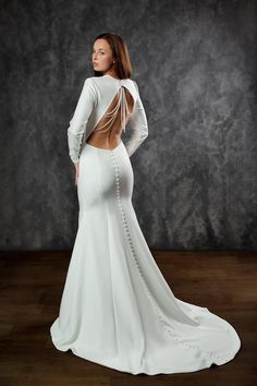 a woman in a white dress standing on a wooden floor with her back to the camera