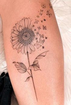 a sunflower tattoo on the thigh with butterflies flying around it and stars in the sky