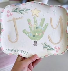 a person holding up a paper plate with a hand painted design on the front and side