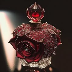 a red rose shaped perfume bottle with diamonds on it's top and the lid