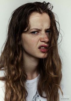 a woman with long brown hair and blue eyes has her face covered in wrinkles