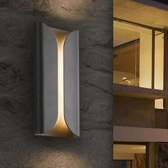 an outdoor wall light that is on the side of a building at night and in front of a house