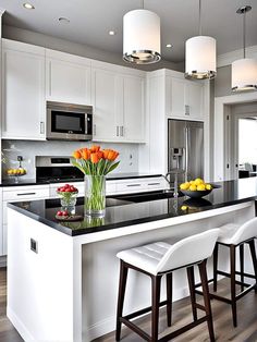 a kitchen with white cabinets, black counter tops and two stools in front of the island