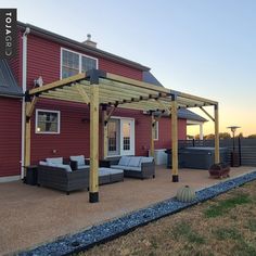 a red house with a covered patio and hot tub in the back yard at sunset