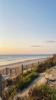 an empty beach at sunset with the ocean in the background