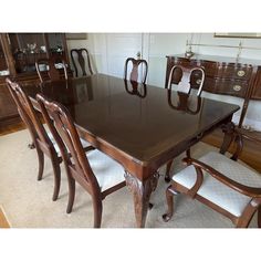 a dining room table with six chairs and a china cabinet in the backround