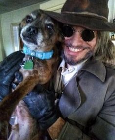 a man in a hat and sunglasses holding a dog