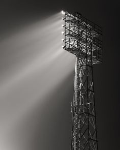 a light shines on the top of a tower in black and white, with beams of light coming from behind it